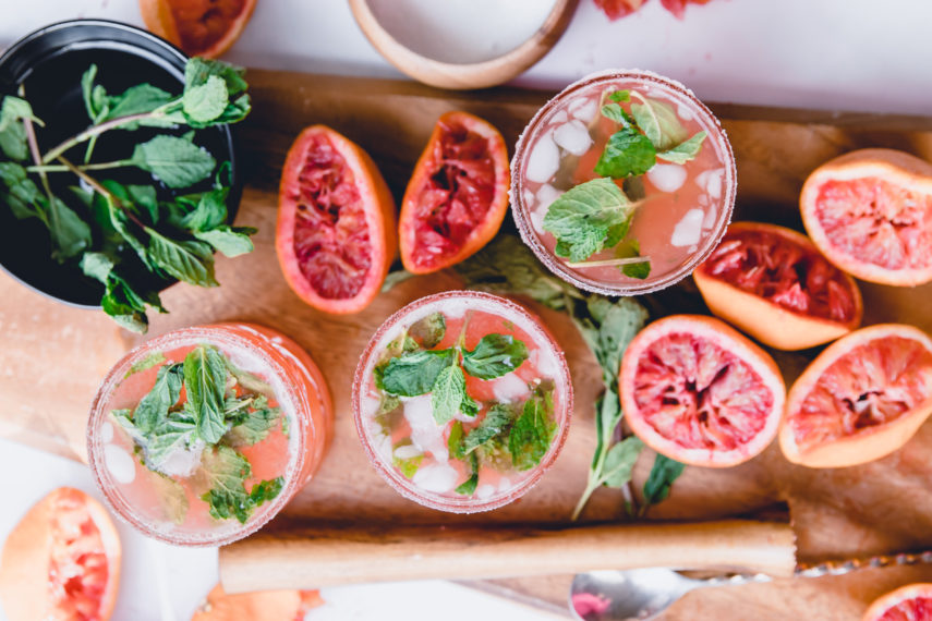 Blood Orange Kombucha Mojito on wooden tray with wooden muddler and mint leaves in a bowl of water