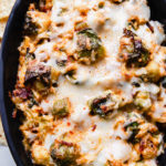 baked hot cheesy brussel sprout and bacon dip in staub